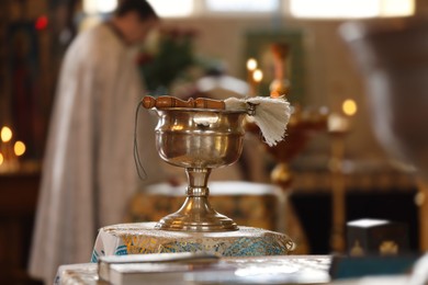 Photo of MYKOLAIV, UKRAINE - FEBRUARY 27, 2021: Vessel with holy water on stand in Kasperovskaya icon of Mother of God cathedral. Baptism ceremony