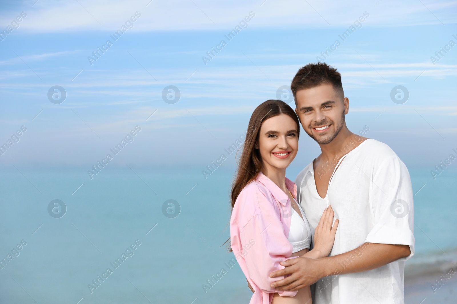 Photo of Young woman in bikini with her boyfriend on beach, space for text. Lovely couple