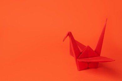 Photo of Origami art. Handmade paper crane on orange background, space for text