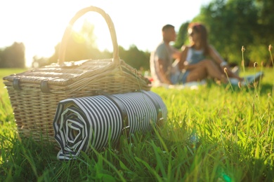 Happy couple on picnic in park, focus on basket