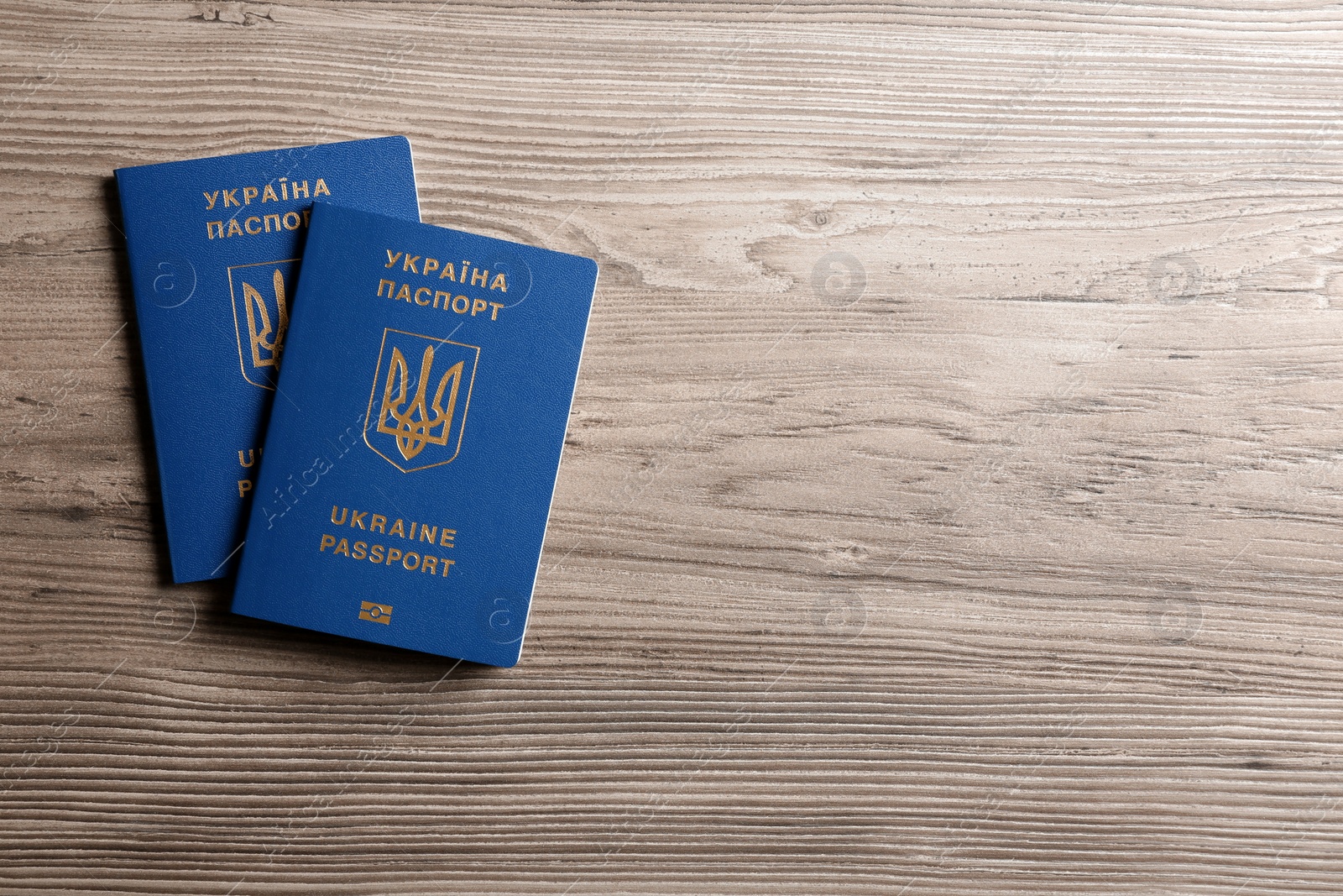 Photo of Ukrainian travel passports on wooden background, top view with space for text. International relationships