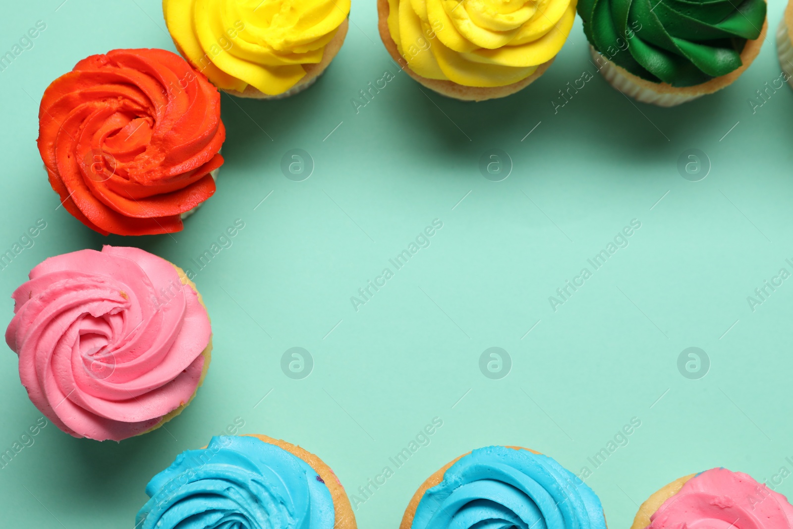 Photo of Delicious cupcakes with bright cream on turquoise background, flat lay. Space for text