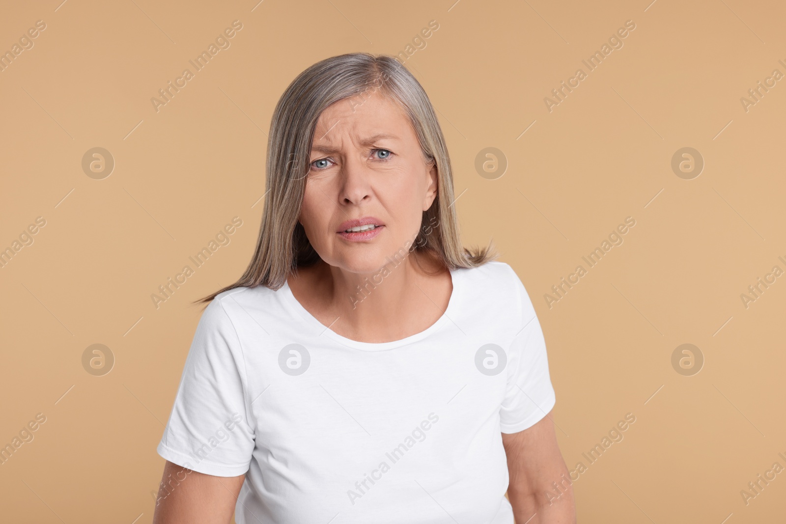 Photo of Portrait of surprised senior woman on beige background