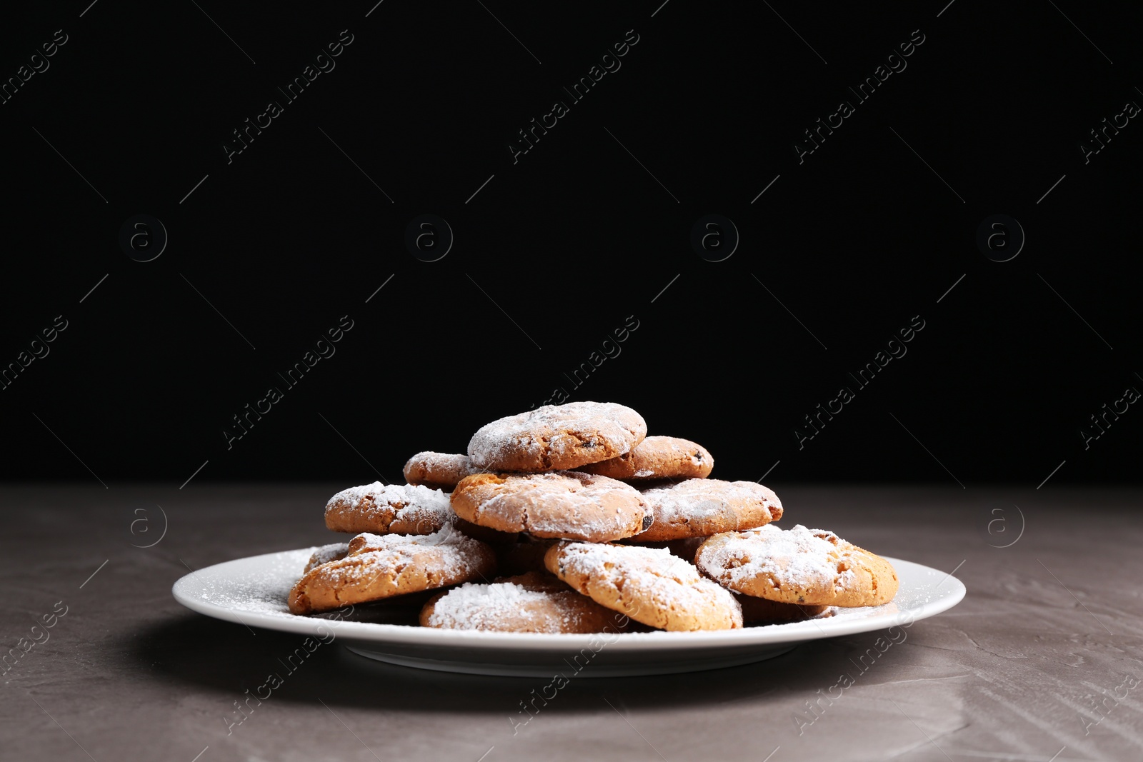 Photo of Tasty cookies with sugar powder on grey textured table, closeup