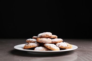 Photo of Tasty cookies with sugar powder on grey textured table, closeup