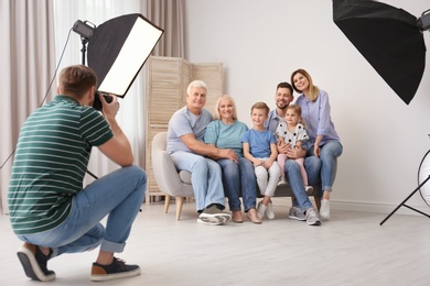 Professional photographer taking photo of family on sofa in studio