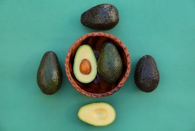 Photo of Tasty fresh avocados on dark turquoise background, flat lay