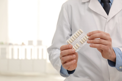 Photo of Professional pharmacist with pills in drugstore, closeup. Space for text