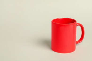 Photo of One red ceramic mug on light grey background, space for text