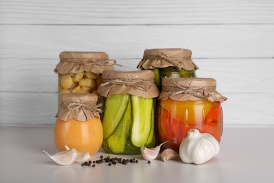 Many jars with different preserved vegetables and mushrooms on light grey table