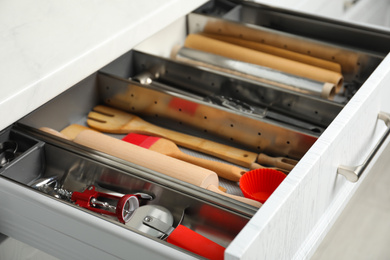 Photo of Different utensils in open desk drawer indoors, closeup