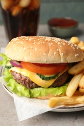 Photo of Delicious burger, soda drink and french fries served on grey table, closeup