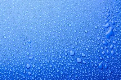 Water drops on blue background, top view