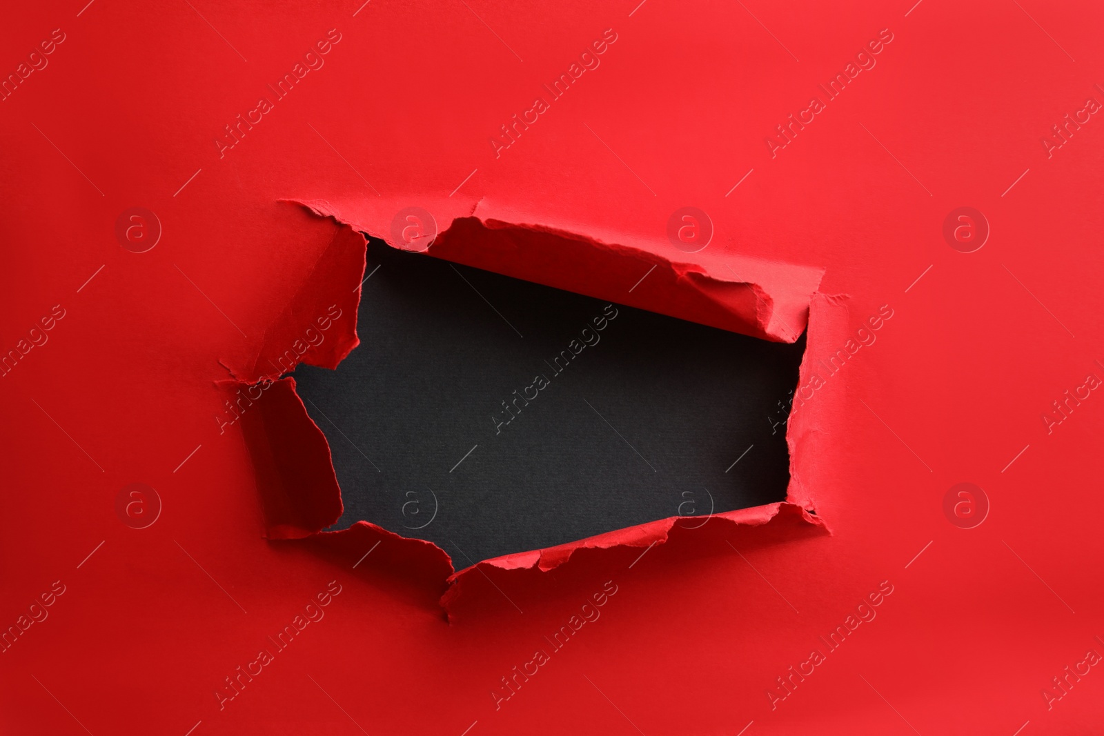 Photo of Hole in red paper on black background