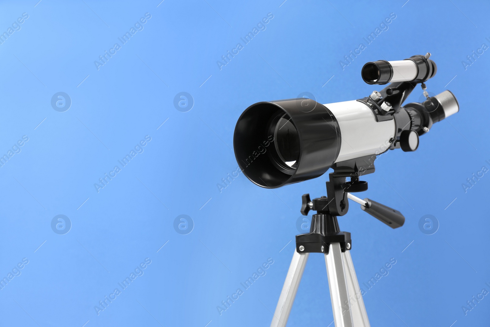 Photo of Tripod with modern telescope on blue background, closeup. Space for text