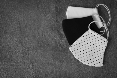 Photo of Homemade protective face masks on grey stone table, flat lay. Space for text