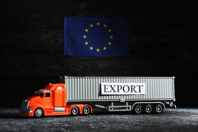 Photo of Toy truck and Europe flag on black background. Export concept