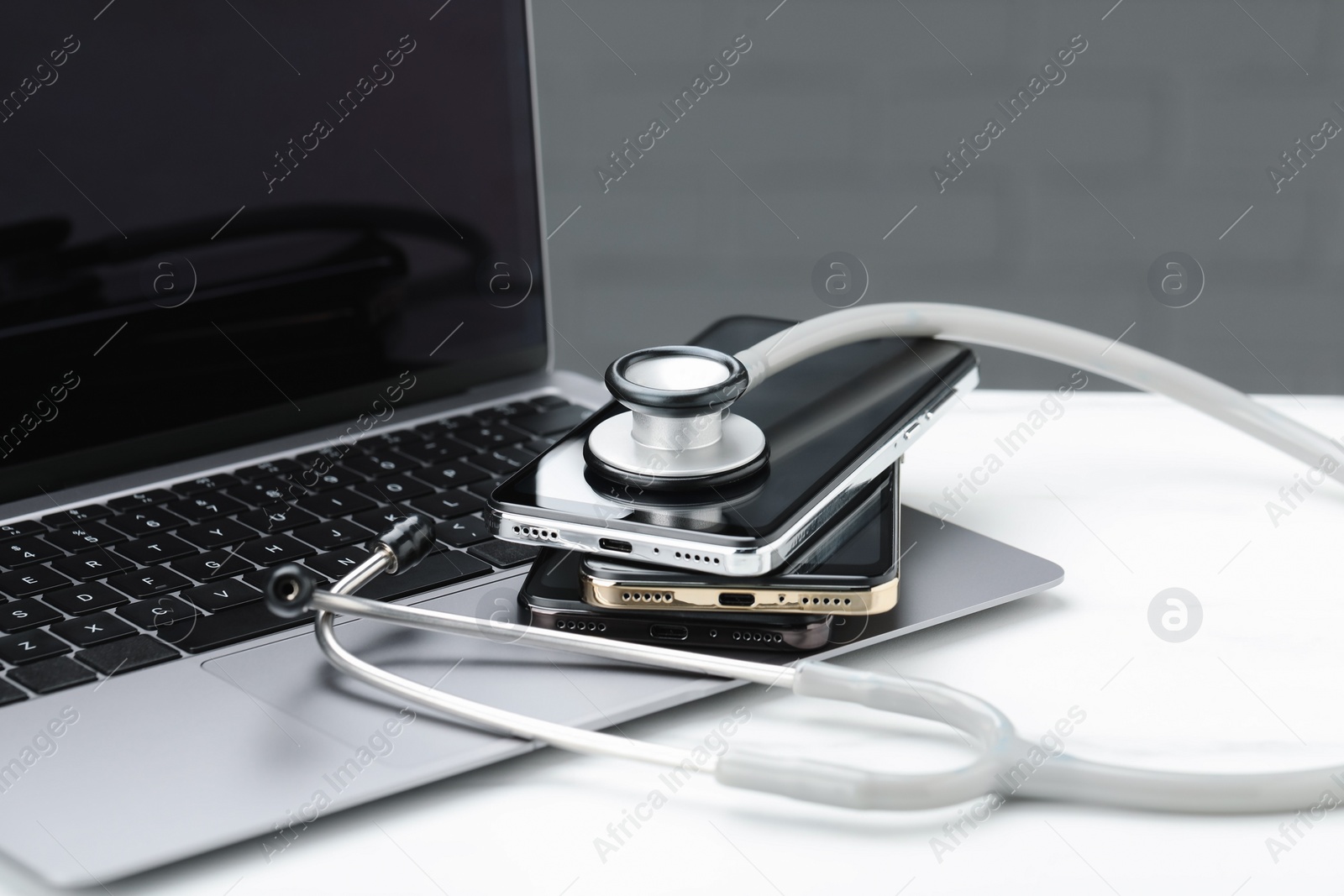 Photo of Stethoscope and modern laptop on white table