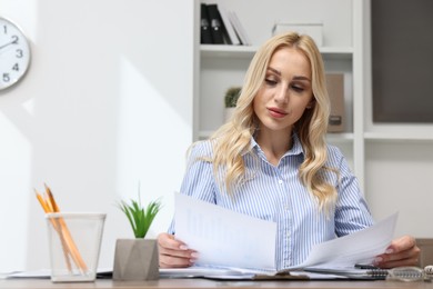 Secretary with documents at table in office