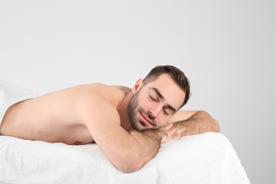 Handsome man relaxing on massage table against white background. Spa service