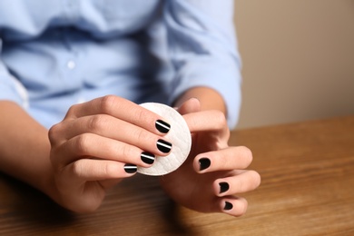 Photo of Woman removing nail polish at table, closeup. Space for text