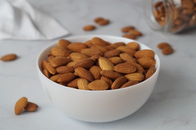Photo of Bowl of delicious almonds on white marble table
