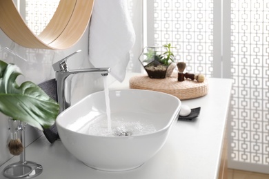 Photo of Sink with running water in stylish bathroom interior
