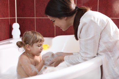 Photo of Happy mother with her little daughter spending time together in bathroom