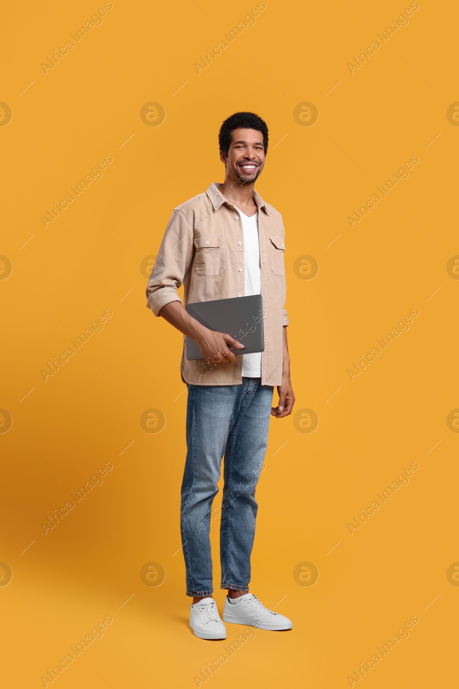 Photo of Happy man with laptop on orange background