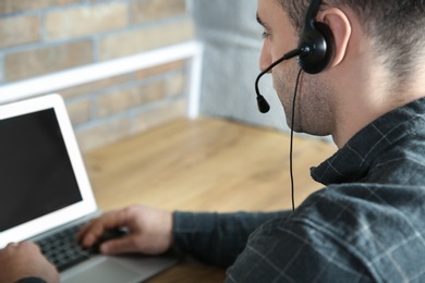 Photo of Male technical support operator with headset at workplace