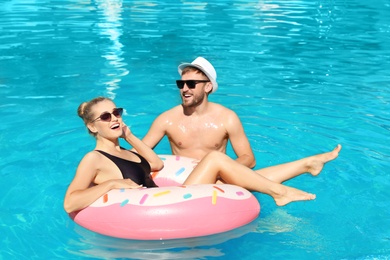 Photo of Happy young couple with inflatable ring in swimming pool