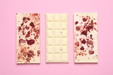 Photo of White chocolate bars with freeze dried fruits on pink background, flat lay