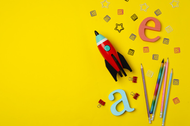 Photo of Bright toy rocket and school supplies on yellow background, flat lay. Space for text