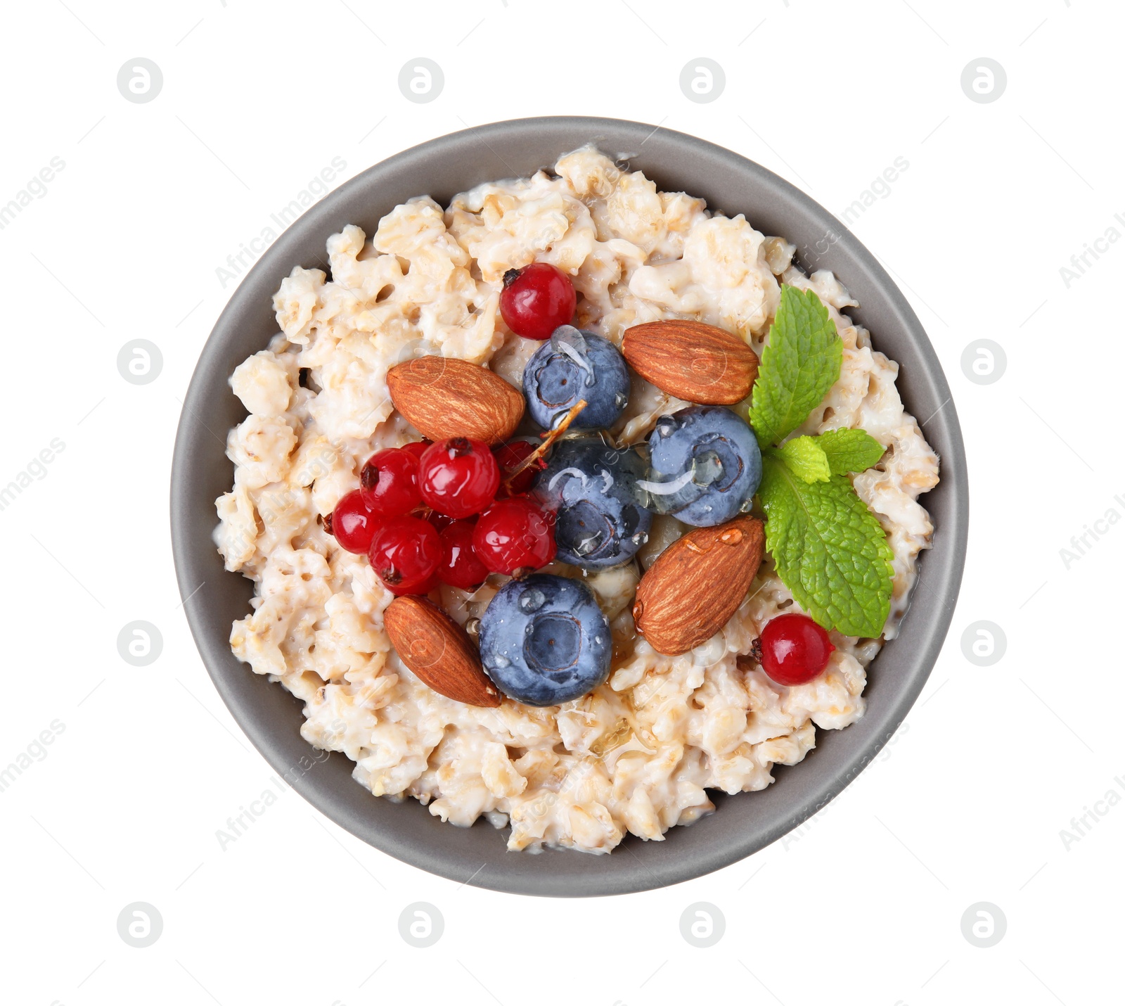 Photo of Ceramic bowl with oatmeal, berries. almonds and mint isolated on white, top view