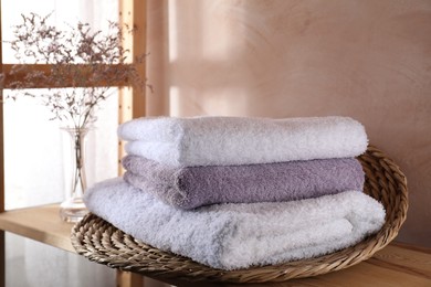 Stacked soft towels and flowers on wooden shelf indoors