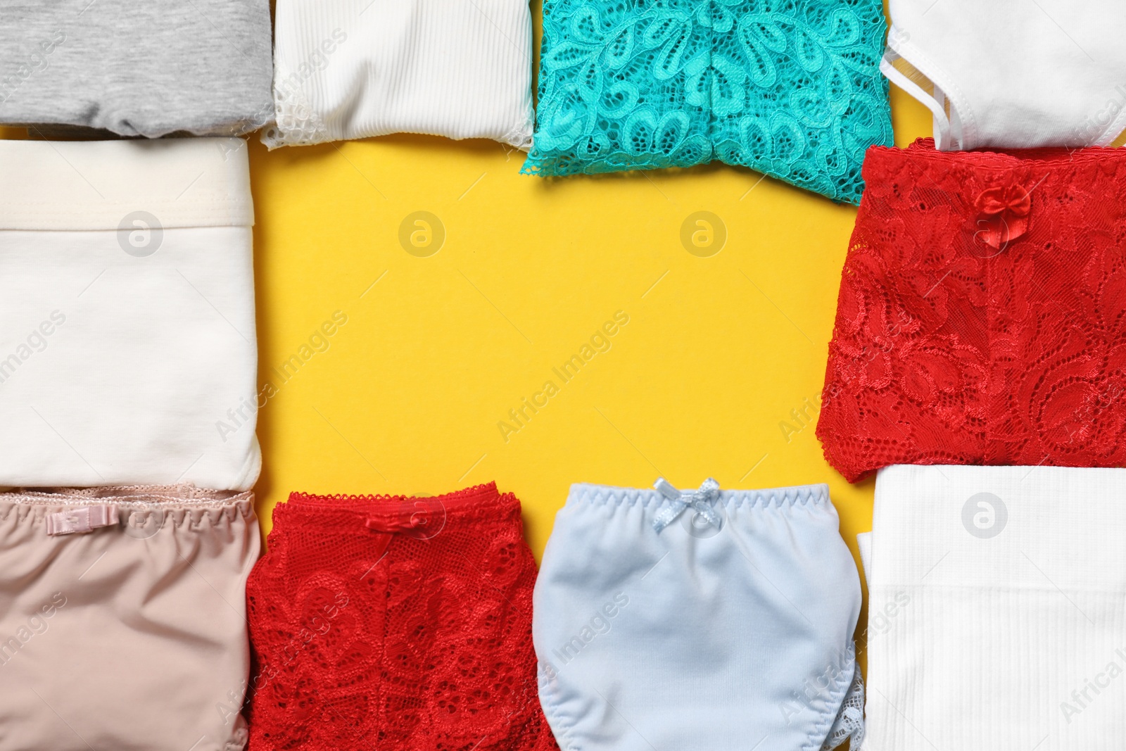 Photo of Frame made of stylish folded women's underwear on yellow background, flat lay. Space for text