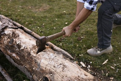 Photo of Man with axe cutting wood outdoors, closeup