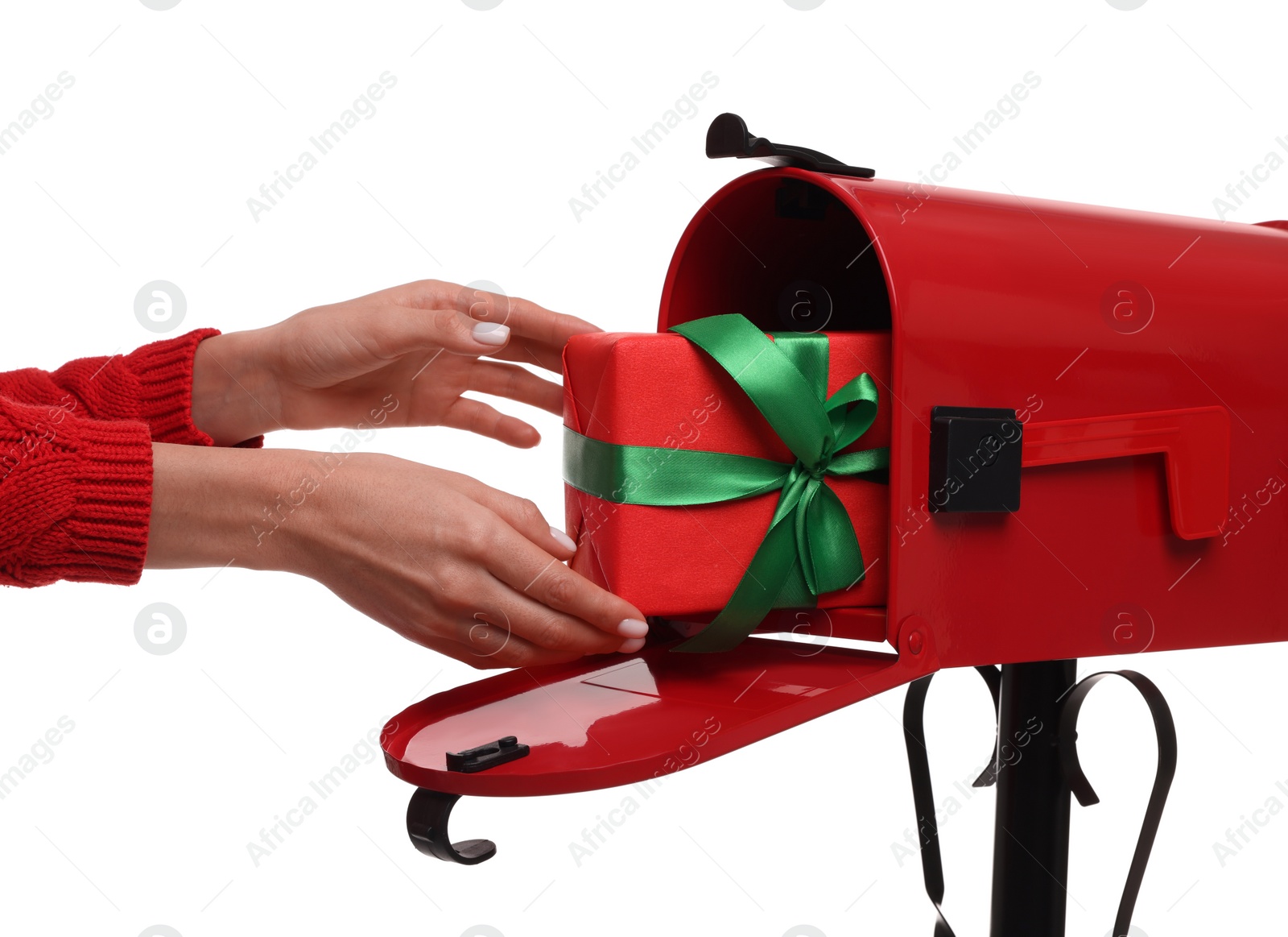 Photo of Woman putting Christmas gift into mailbox on white background, closeup. Sending present by mail