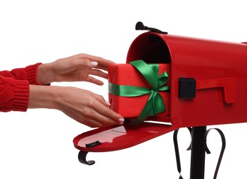 Photo of Woman putting Christmas gift into mailbox on white background, closeup. Sending present by mail