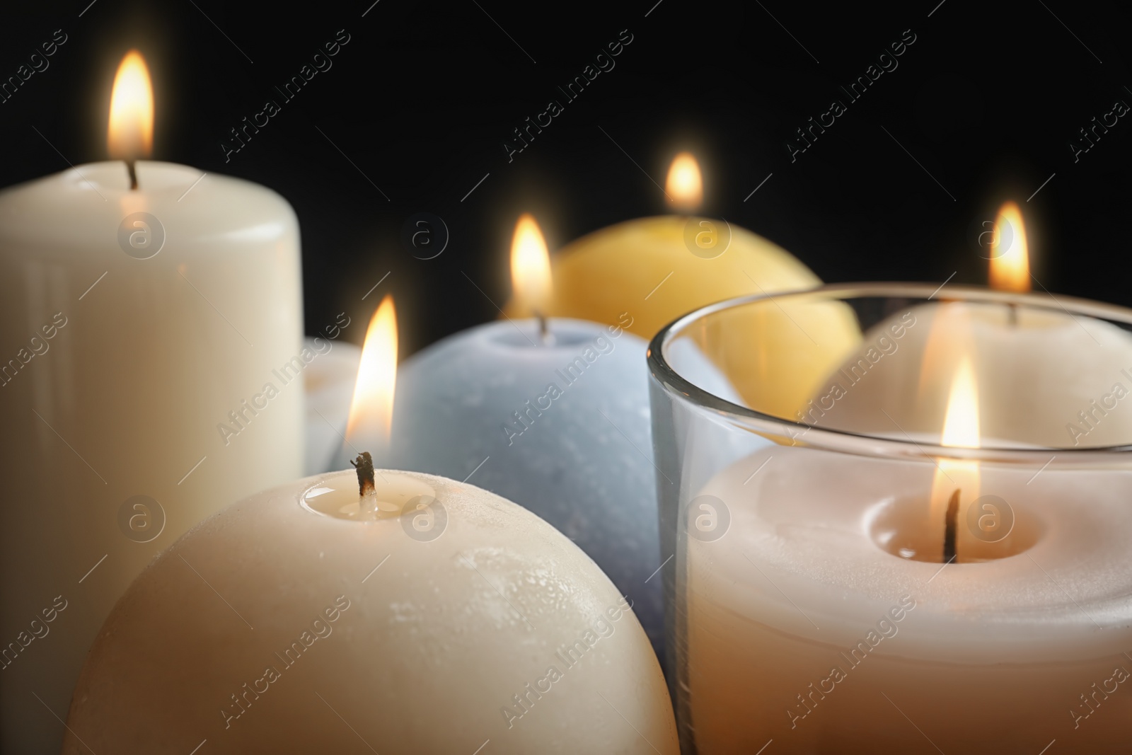 Photo of Burning wax candles of different shapes and colors, closeup