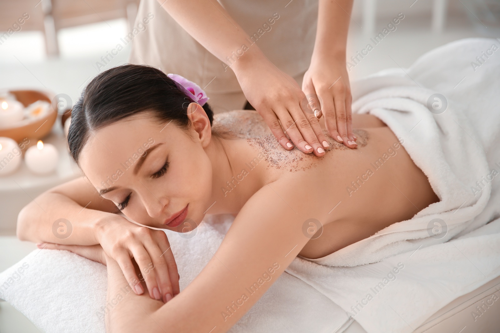 Photo of Beautiful young woman having massage with body scrub in spa salon