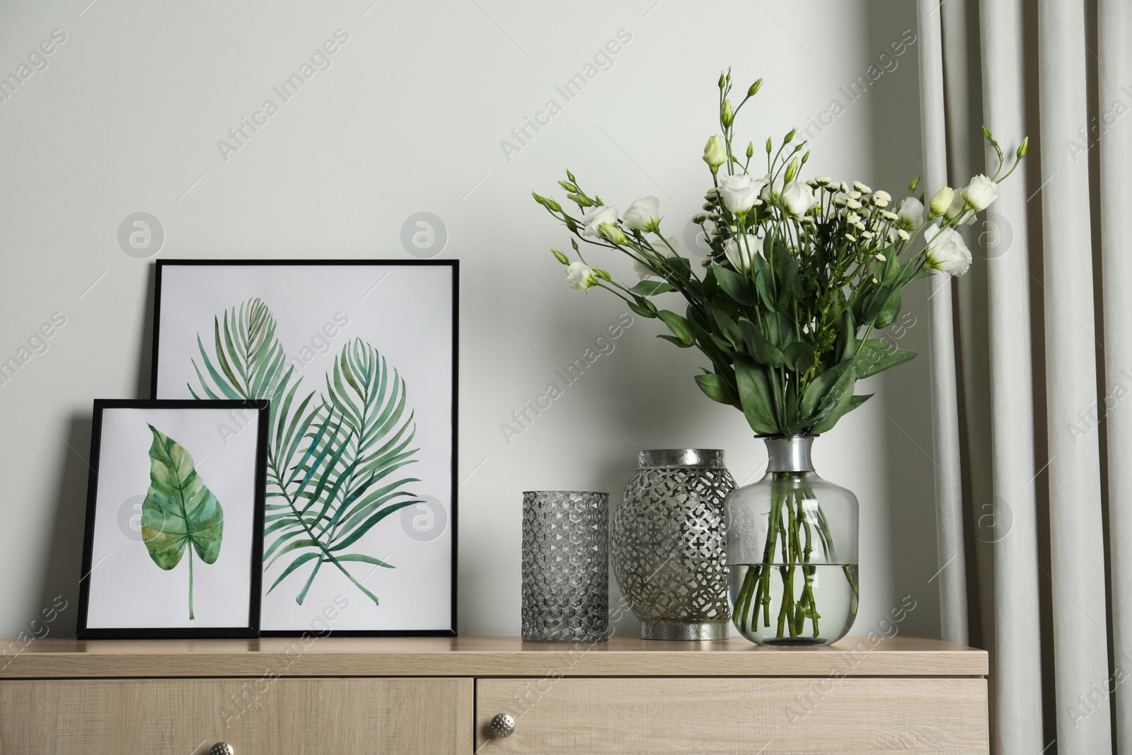 Photo of Decorative vases and pictures on commode indoors