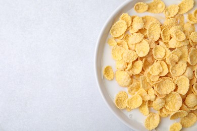 Photo of Breakfast cereal. Corn flakes and milk in bowl on light grey table, top view. Space for text