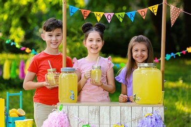 Cute little children at lemonade stand in park. Summer refreshing natural drink