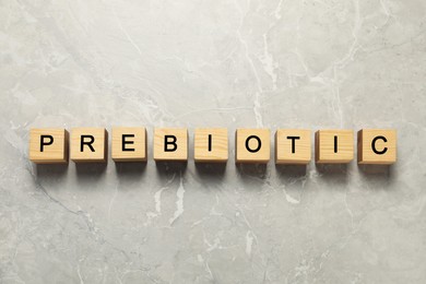 Wooden cubes with word Prebiotic on light grey marble table, flat lay