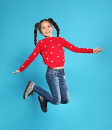 Photo of Portrait of little girl jumping on color background