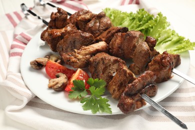Delicious shish kebabs with vegetables on table