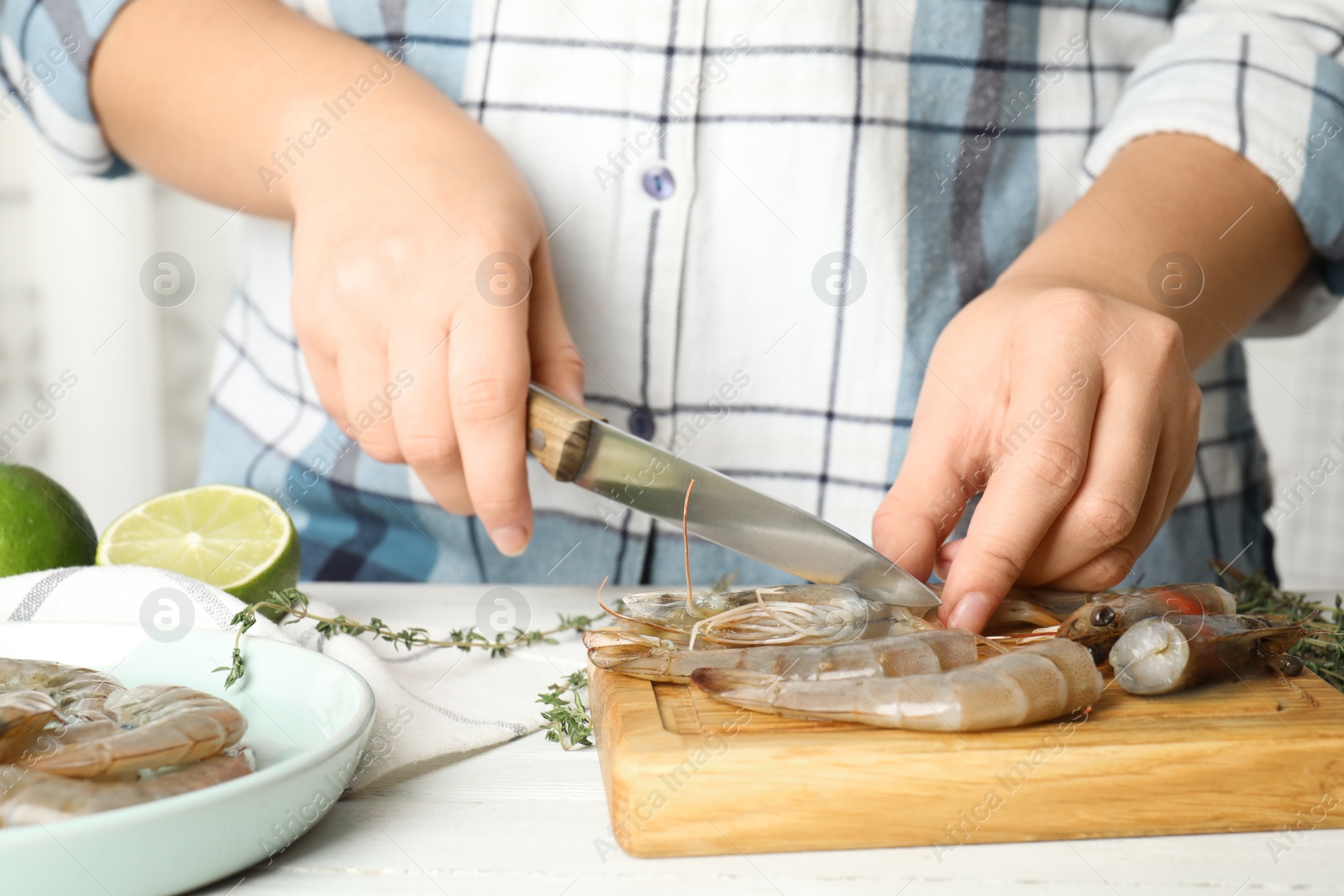 Photo of Woman cutting fresh shrimp at table, closeup