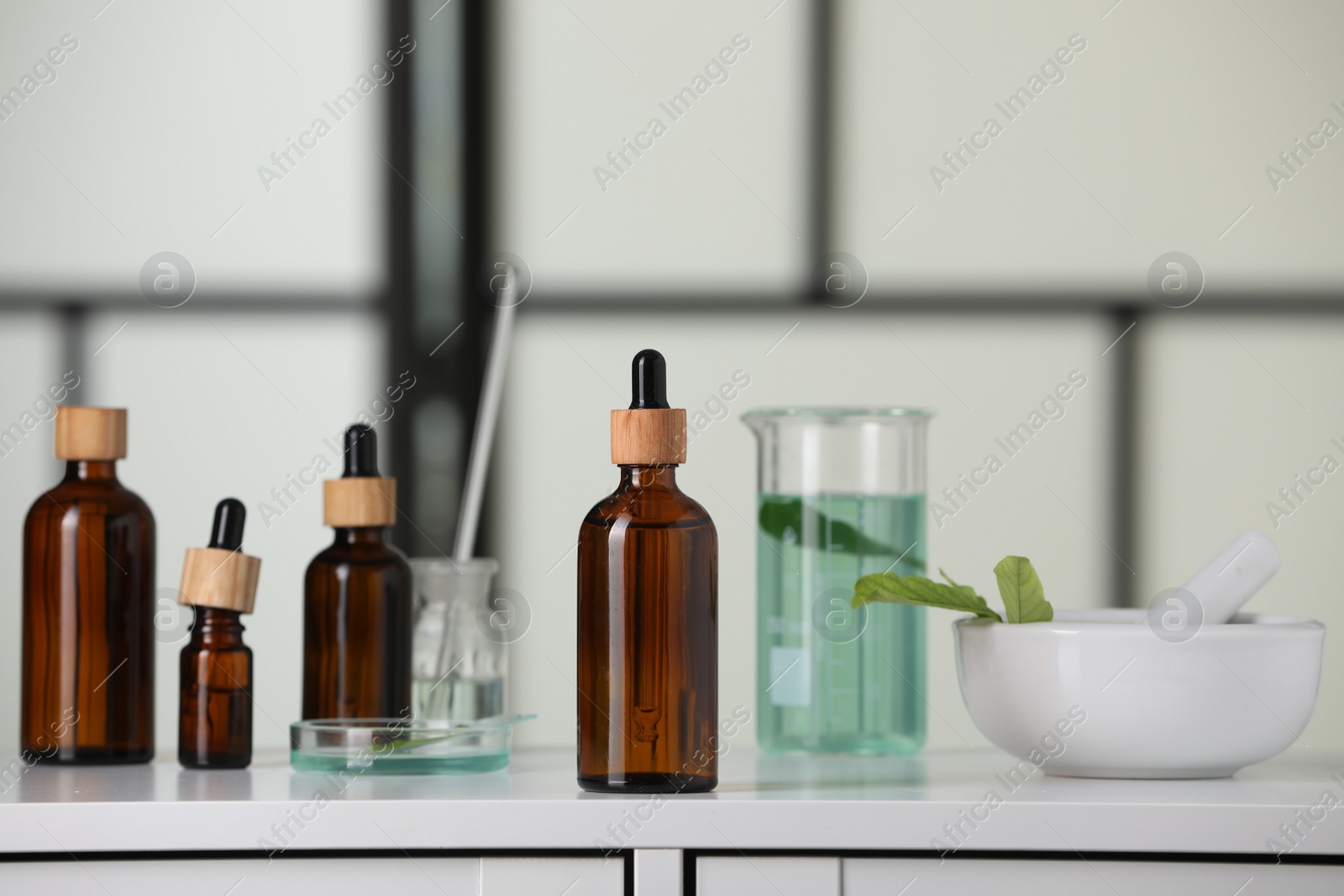 Photo of Bottles and glass tubes with leaves on white lab drawer indoors