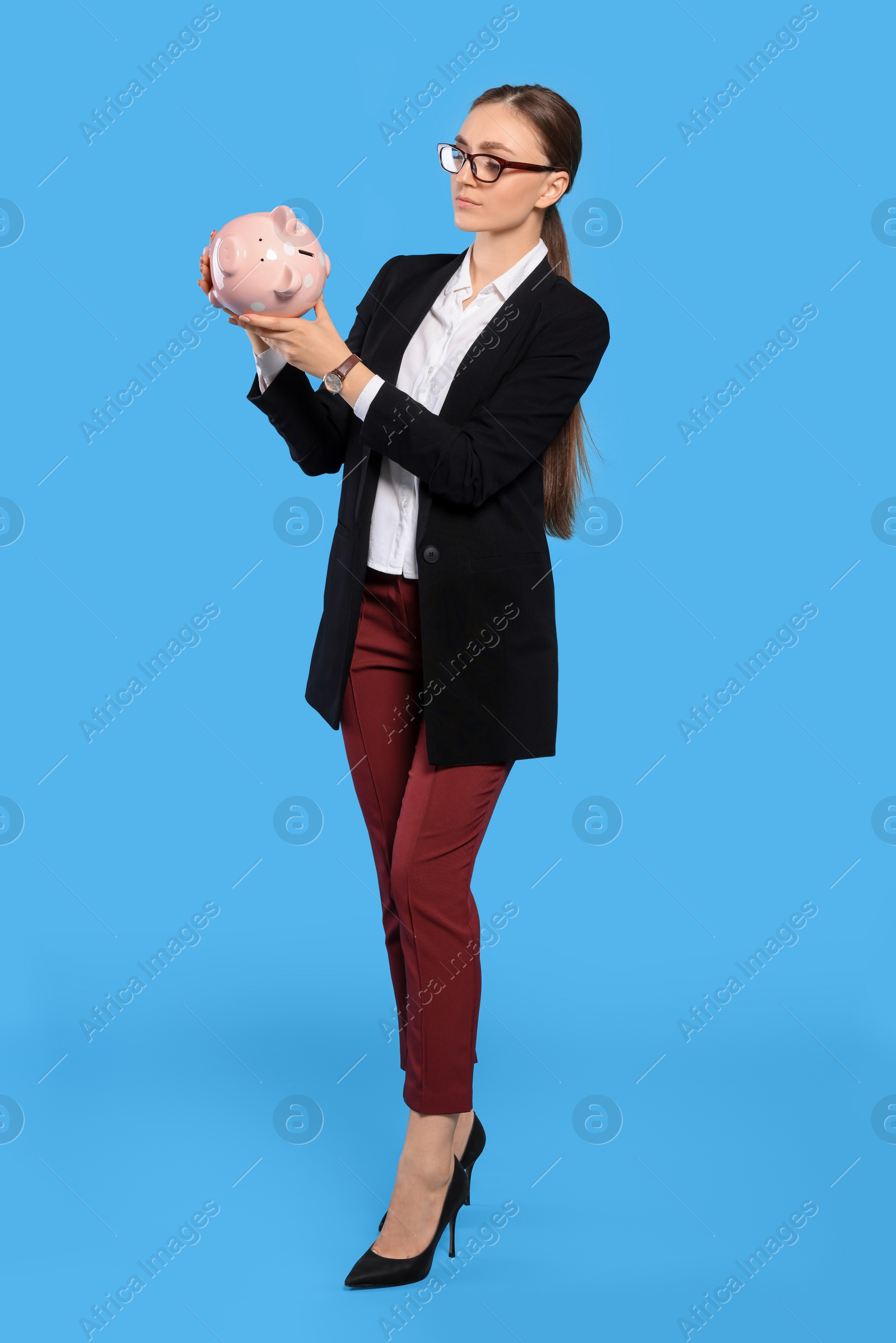 Photo of Sad young businesswoman with piggy bank on light blue background